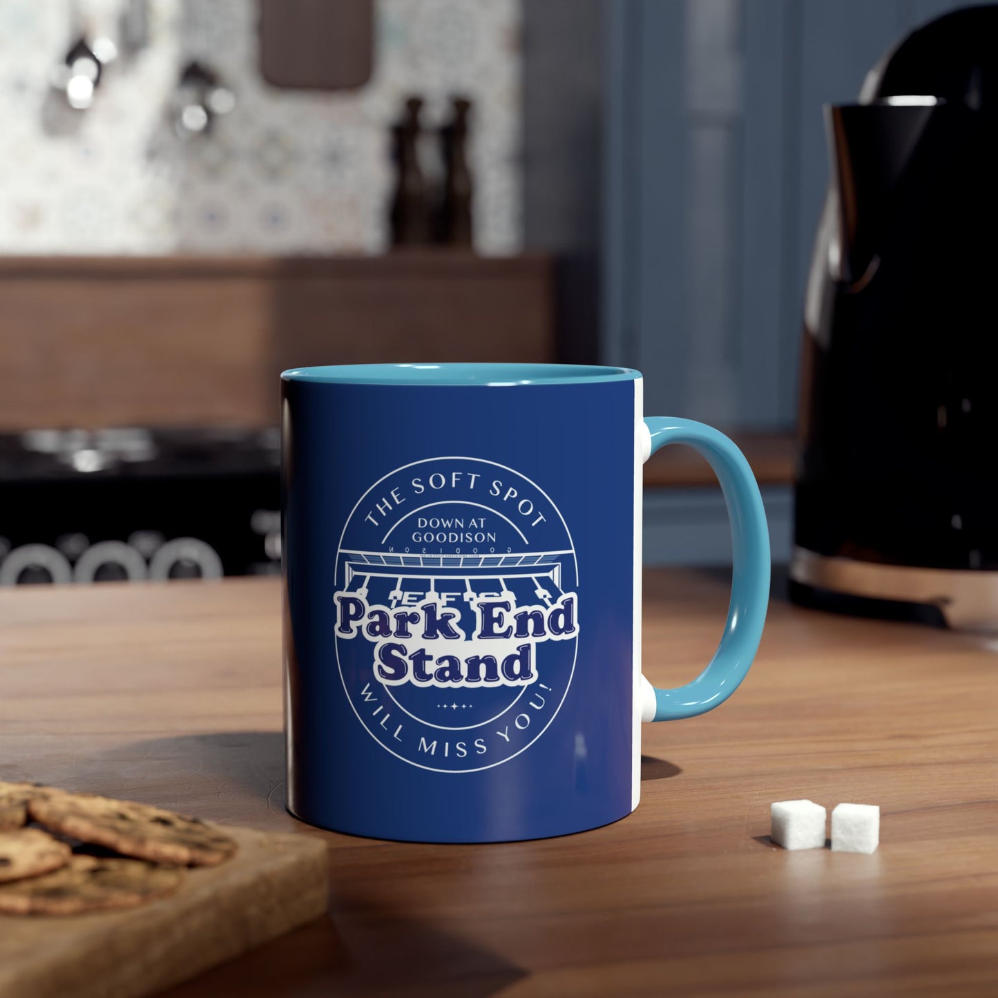 Light blue handle and infill. this is a lifestyle shot showing the mug in a kitchen environment with a kettle, sugar lumps, a cooker and a board with cookies on it.