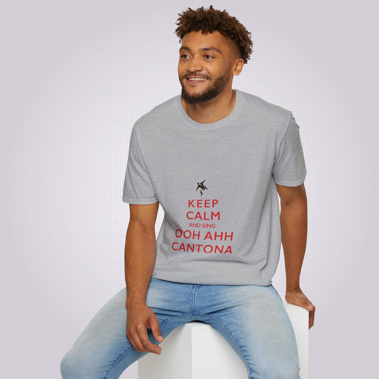 Young mixed race male in his twenties sits on a white box wearing the sport grey t shirt and a pair of jeans he is smiling as he looks at someone off camera
