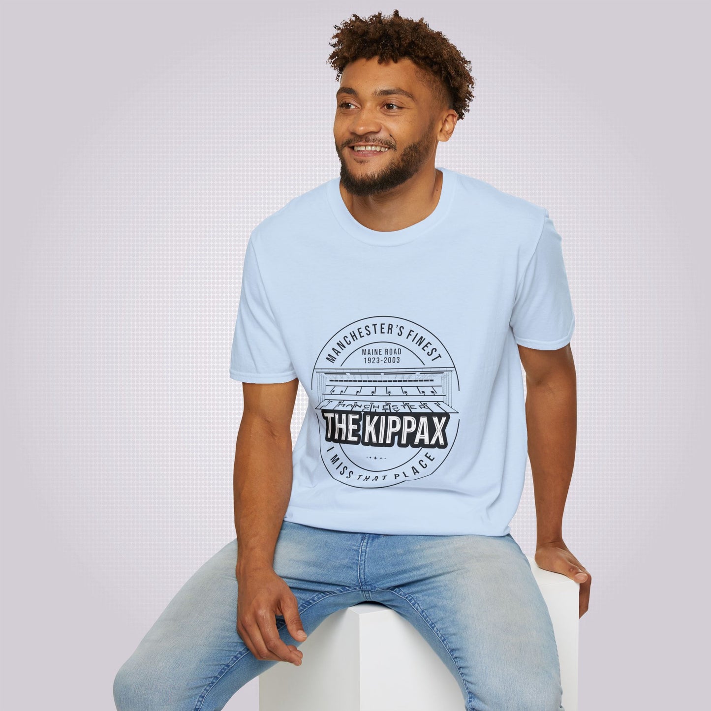Young mixed race man sits on a white box wearing the light blue t shirt with a pair of jeans