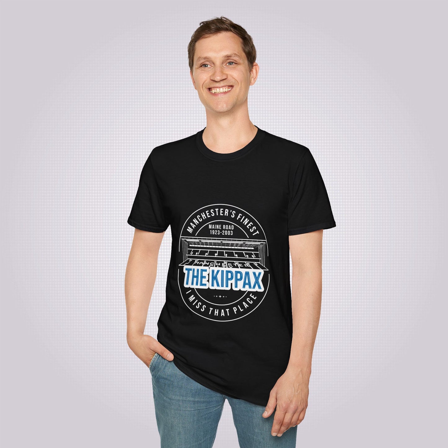 Young male model stands smiling at someone off camera with one hand in his pocket whilst the other is by his side he is modelling the black t shirt with a pair of jeans