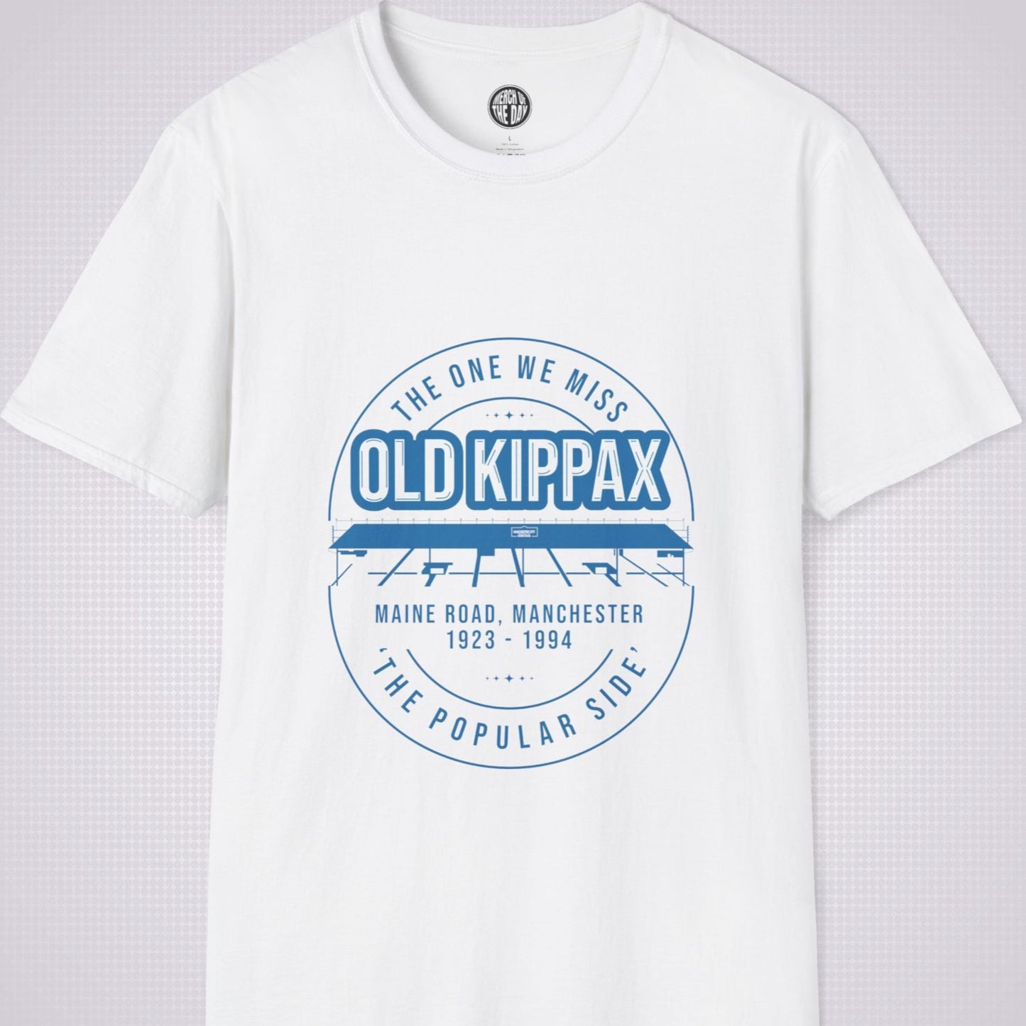 White T Shirt on a light grey dotted background. There is an illustration of the Old Kippax stand as the focal point of the design, with the following text written above the drawing: 'The One We Miss' OLD KIPPAX. Then under the diagram it reads Maine Road, Manchester 1923 - 2004 followed by the words 'The Popular Side’