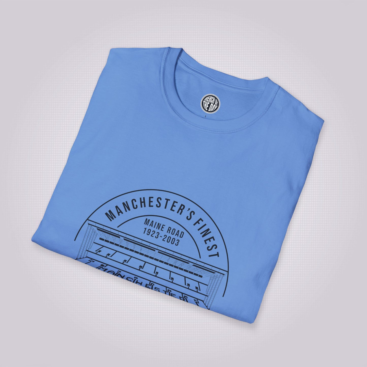 Mid Blue T Shirt folded up and placed at a slight right angle on a light grey dotted background