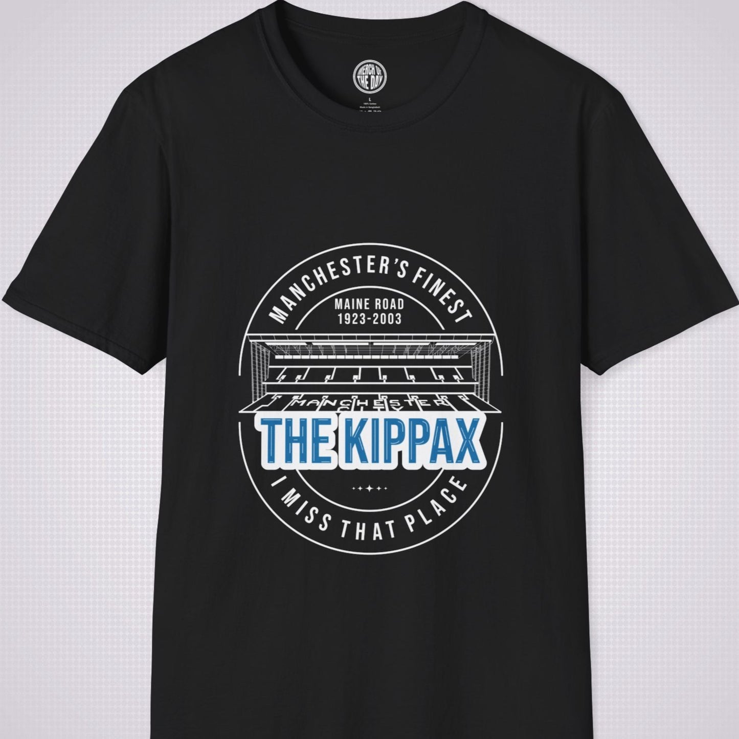 Black T Shirt on a light grey dotted background. There is an illustration of the Kippax Stand, above the illustration it reads 'Manchester's Finest Maine Road 1923 to 2003'. Below the illustration it reads 'The Kippax I miss that place'