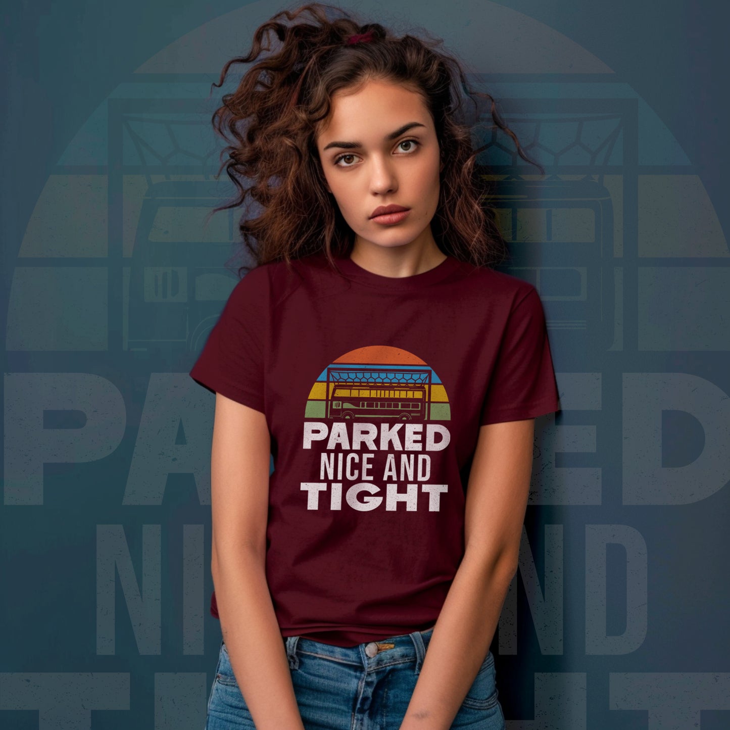 Lifestyle picture showing a young woman in her twenties stood against a blue wall which has the shirt graphic pasted onto it faintly she is wearing the maroon t shirt with a pair of jeans