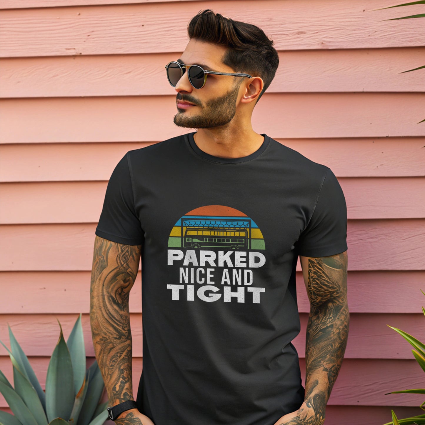 Young man stood against some fence panels glances to his right wearing a pair of sunglasses with the black t shirt
