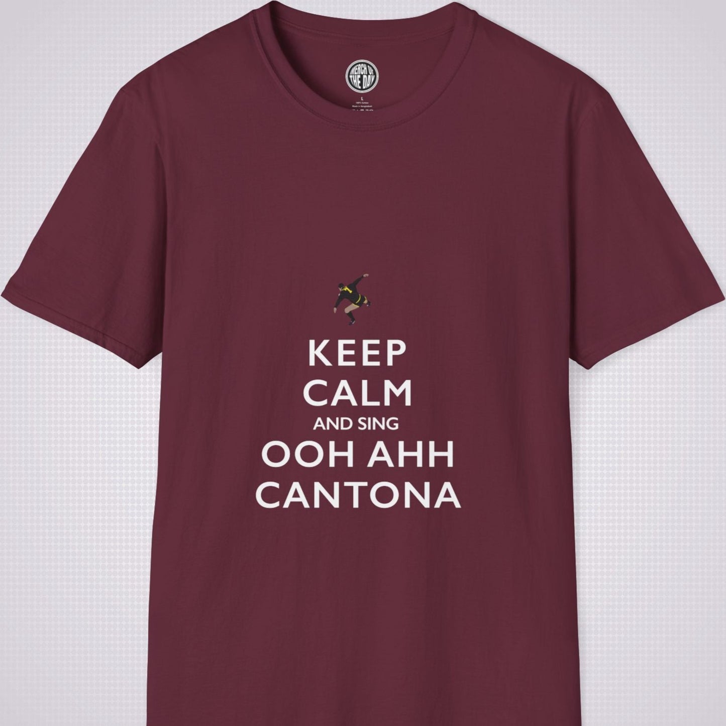 Burgundy T Shirt on a light grey dotted backdrop. The design on the shirt is done in the keep calm style which reads 'Keep Calm And Sing Ooh Ahh Cantona' in red text, with a cartoon graphic of Eric's famous kung fu kick above it.