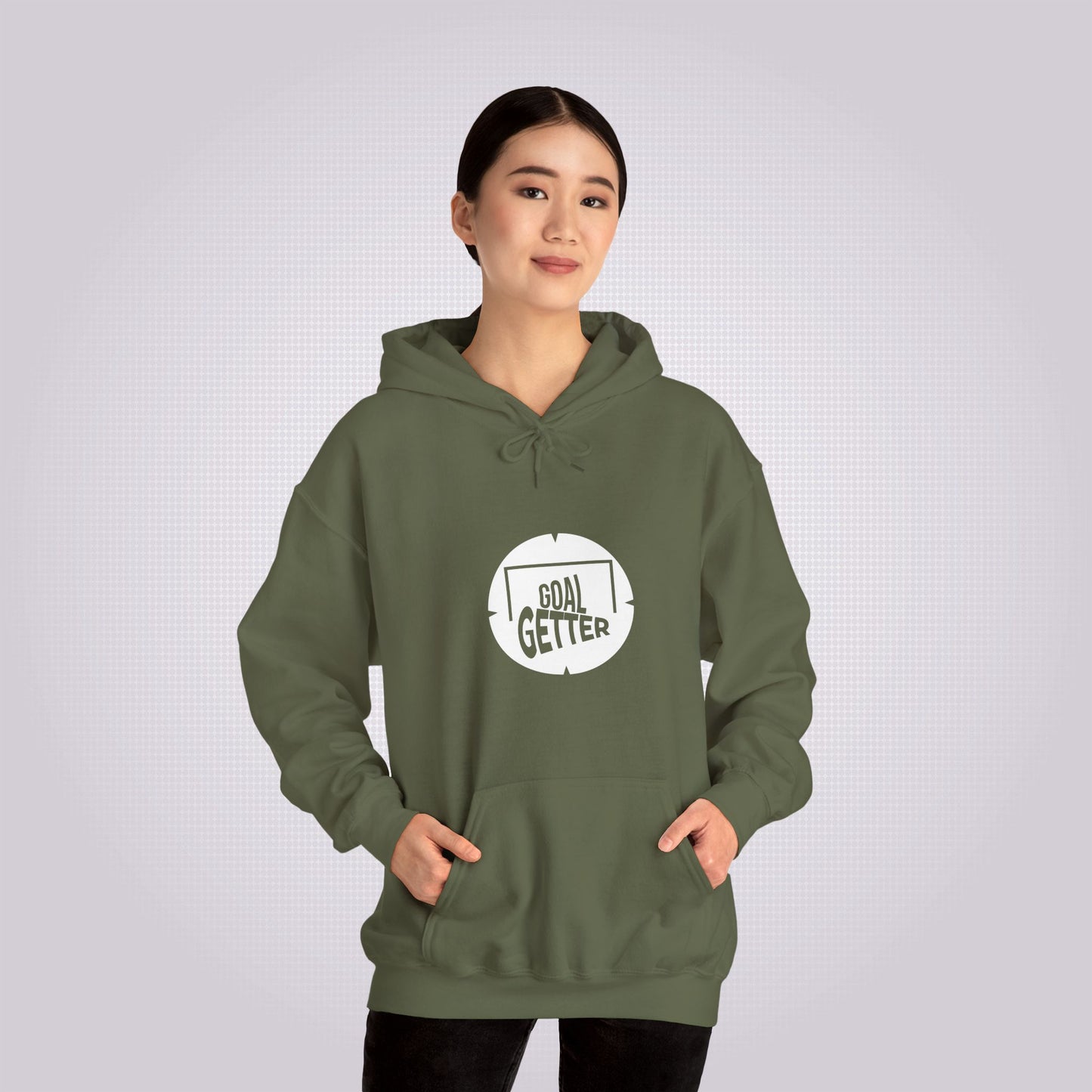 Young chinese woman smiles at camera with both hands in pocket demonstrating the pouch design she is wearing the military green variant and black jeans