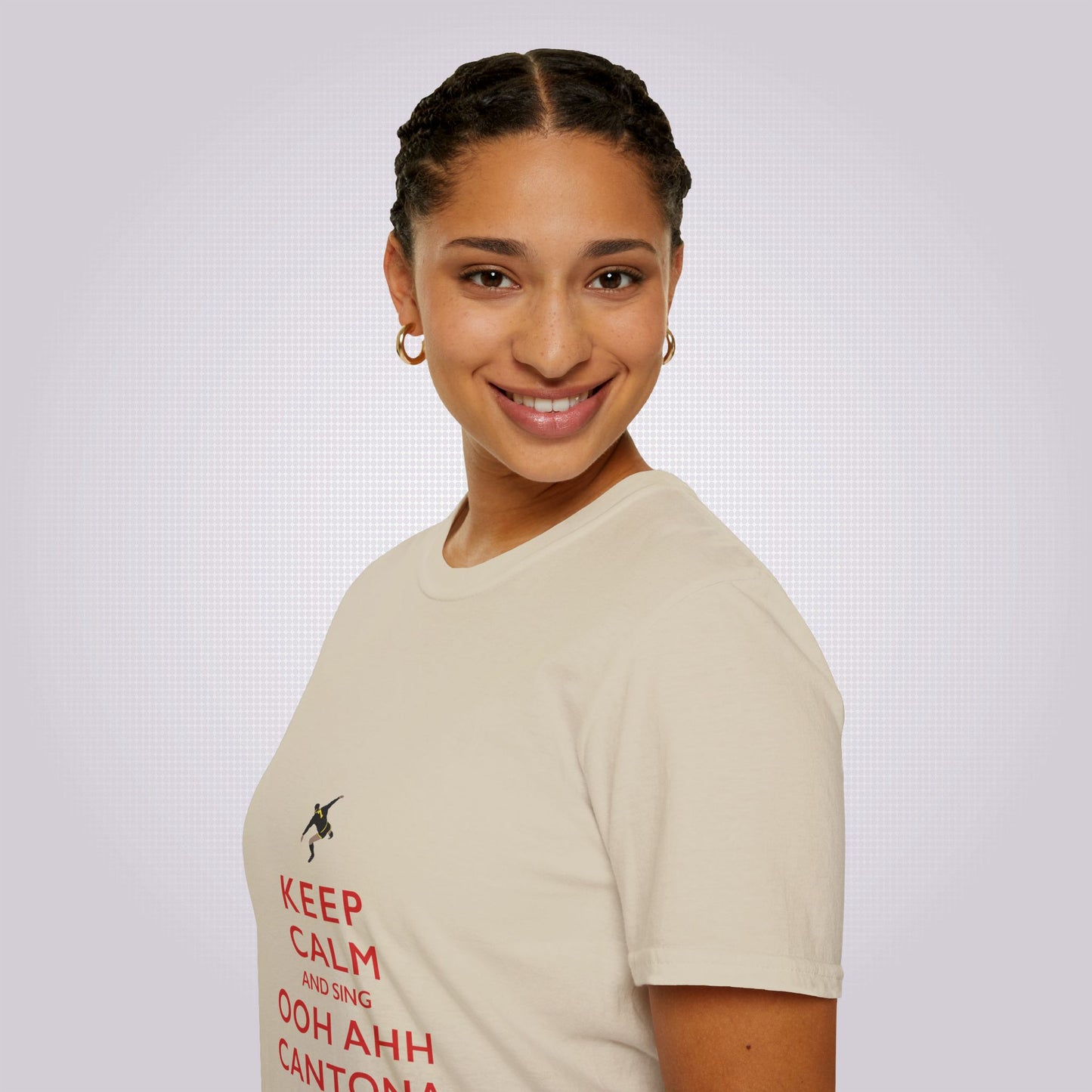 Side profile picture featuring a mixed race woman in her twenties wearing the sand coloured t shirt, her body is facing to the left of the camera but her face is turned towards the camera as she smiles.