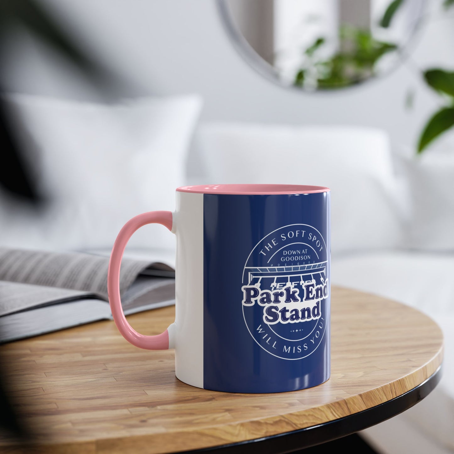 Shows the mug in a living room environment demonstrating the pink handle and infill