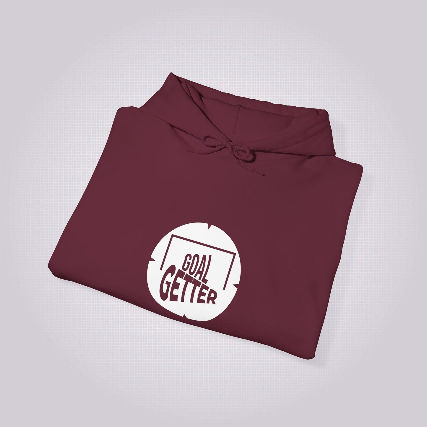 Maroon hoodie folded up and placed at a right angle on a light grey patterned background