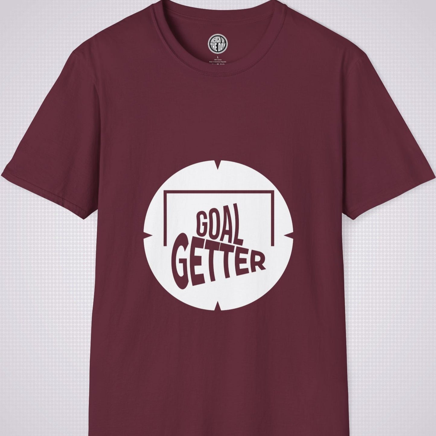 Maroon t shirt on a light grey patterned background the artwork on the shirt shows a circle with segments in all 4 corners symbolising a target and a football  and the words read goal getter within a goal frame 