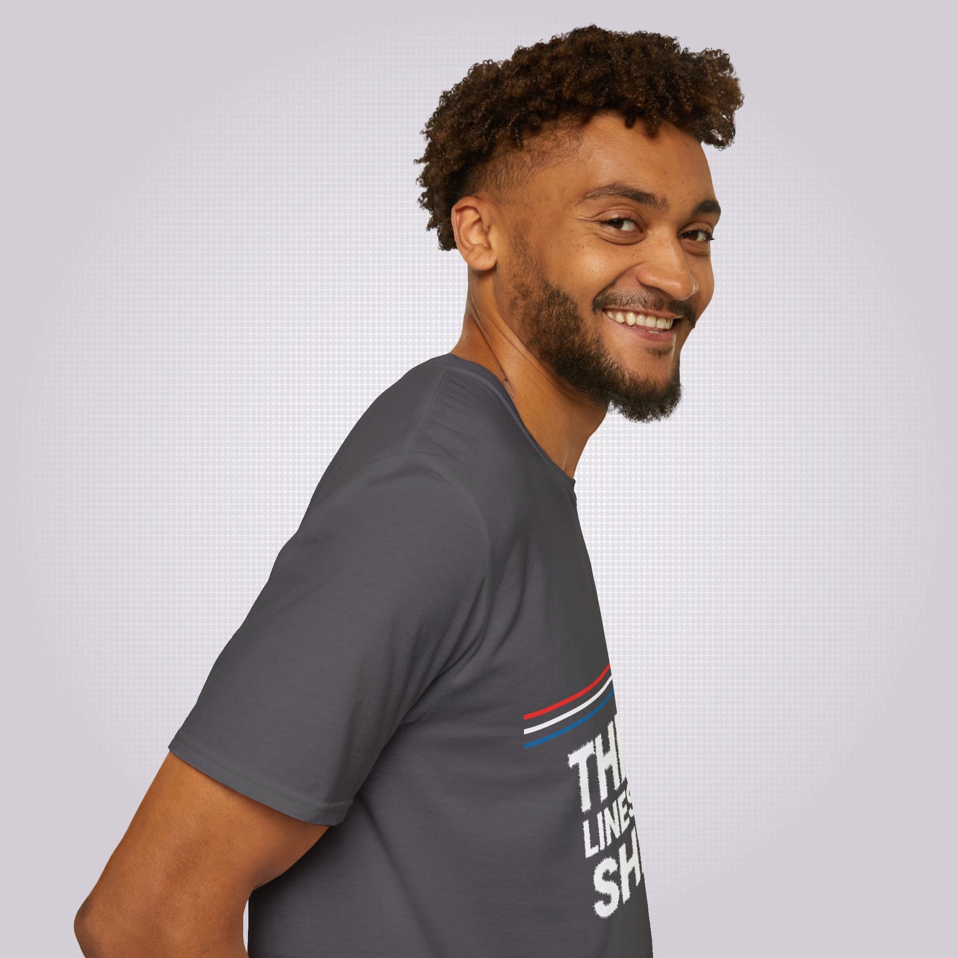 Side profile picture featuring a mixed race guy in his twenties his body is facing to the right as you look but his head is turned towards the camera he is wearing the charcoal t shirt