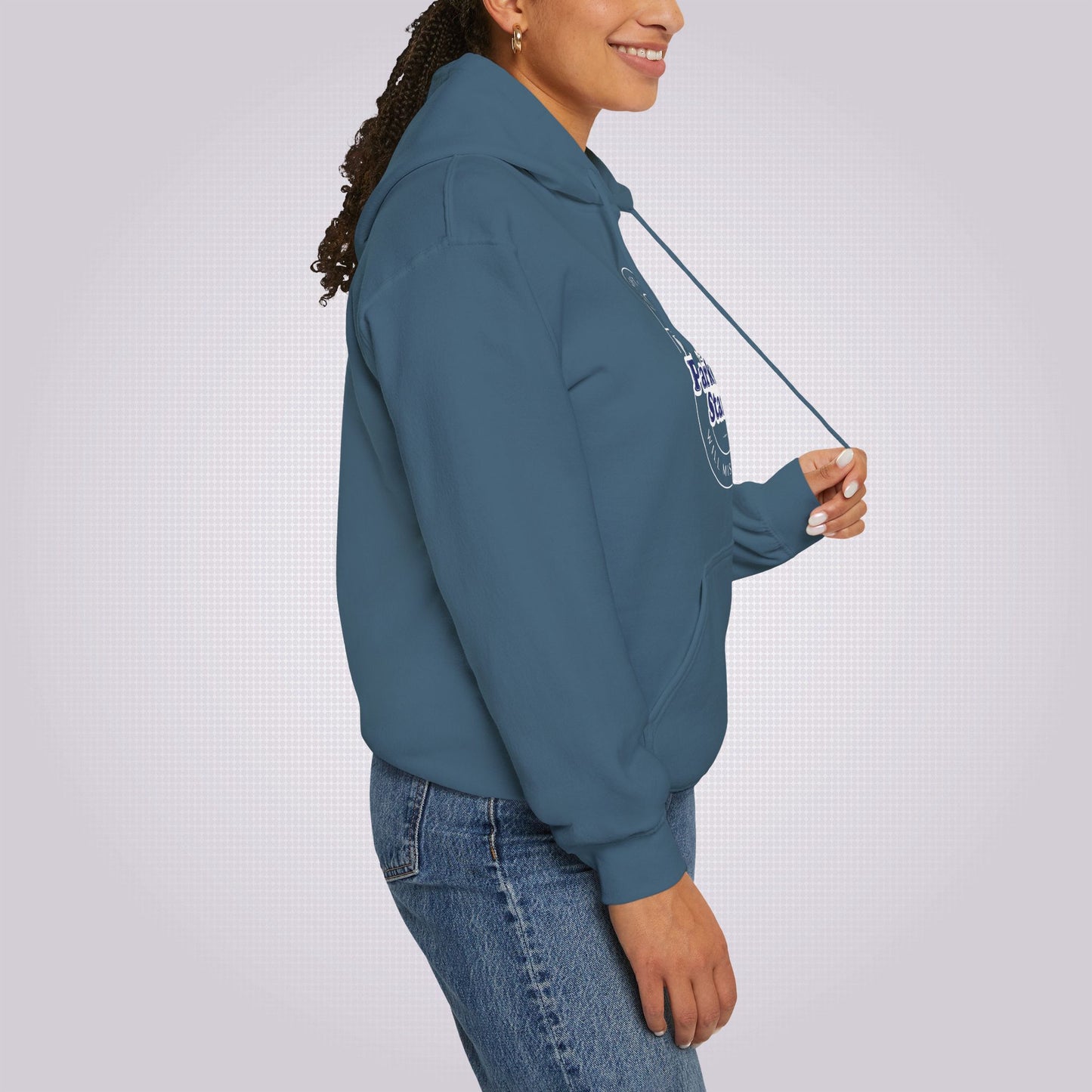 Side profile picture featuring a young mixed race girl in her twenties she is wearing the Indigo Blue hoodie and a pair of Jeans, she is facing to the right of the screen and is demonstrating the drawcord feature of the product.