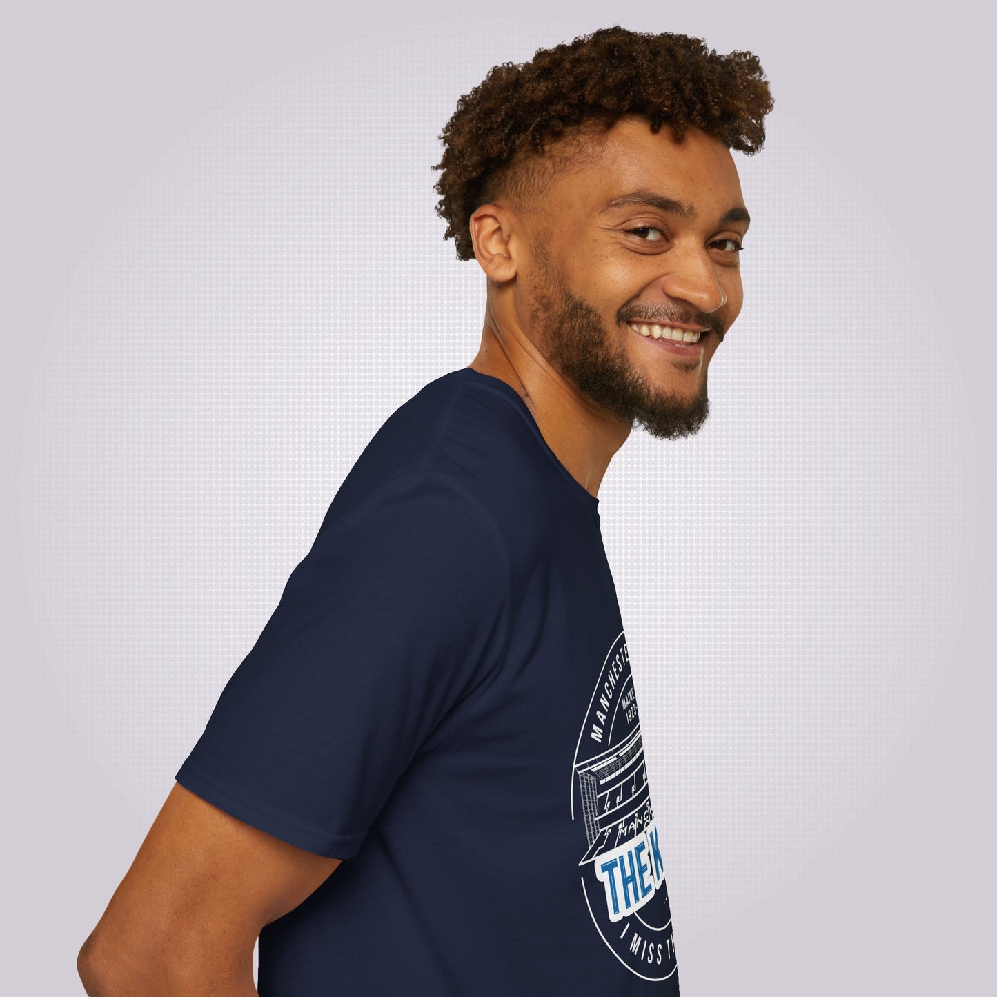 Side profile picture featuring a young mixed race male his body facing to the right of the screen but his head is turned towards the camera, he is wearing the navy blue t shirt