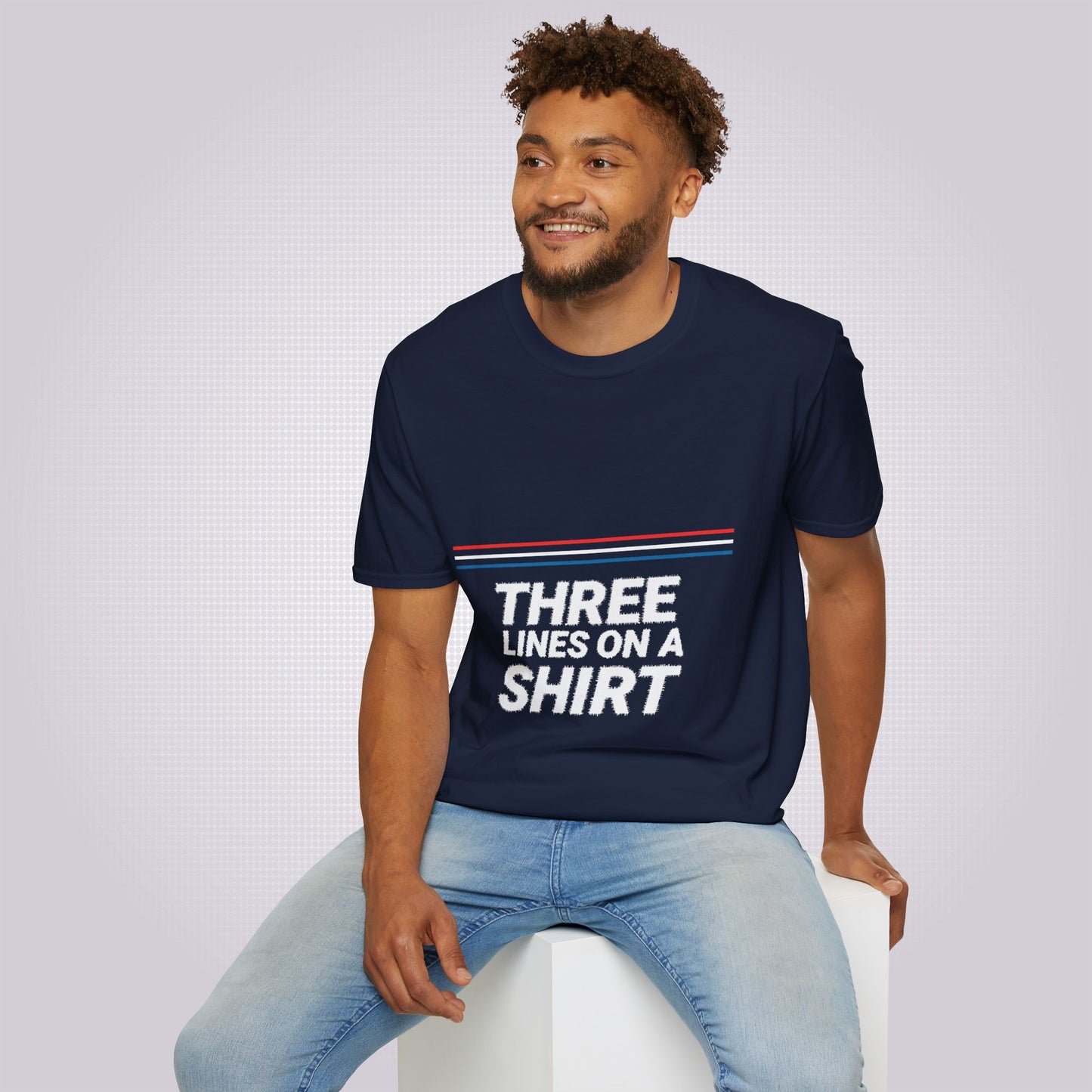 Young mixed race male model sits on a white box wearing the navy t shirt and jeans