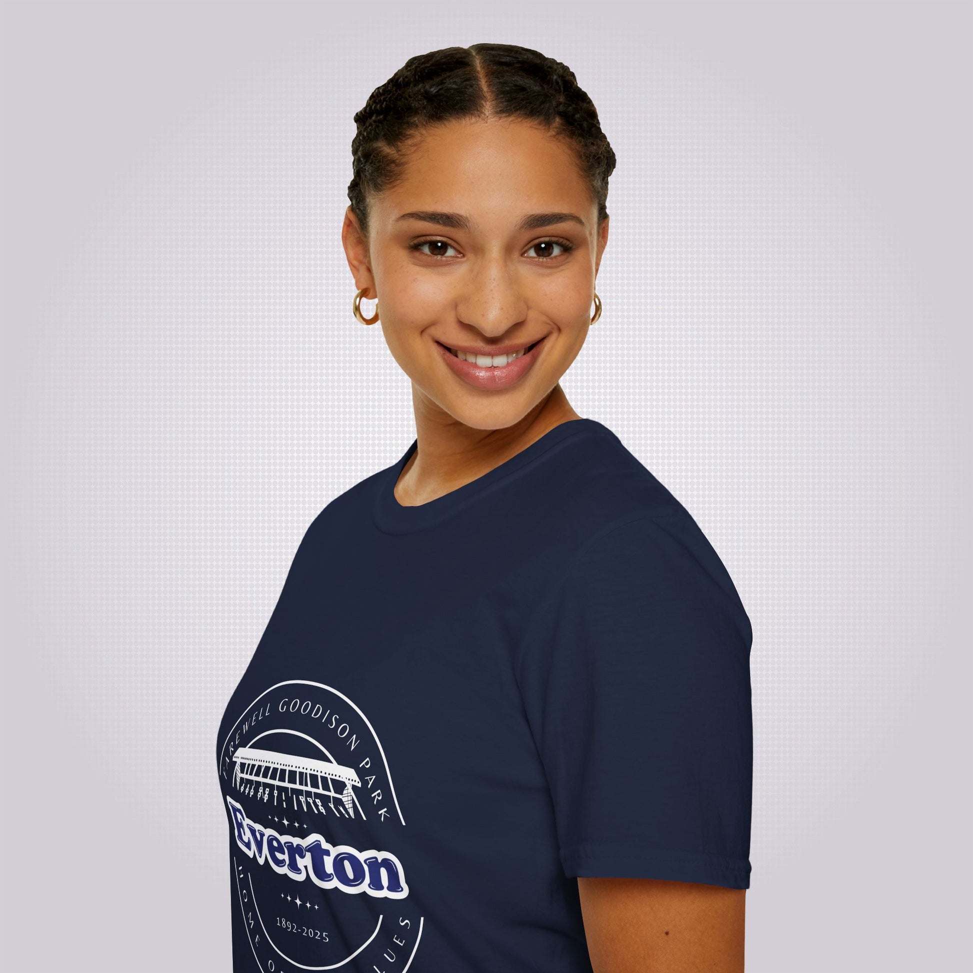 Side profile picture featuring an attractive young mixed race girl standing with her body facing to the left as you look but with her head turned towards the camera as she smiles and she is wearing the navy t shirt