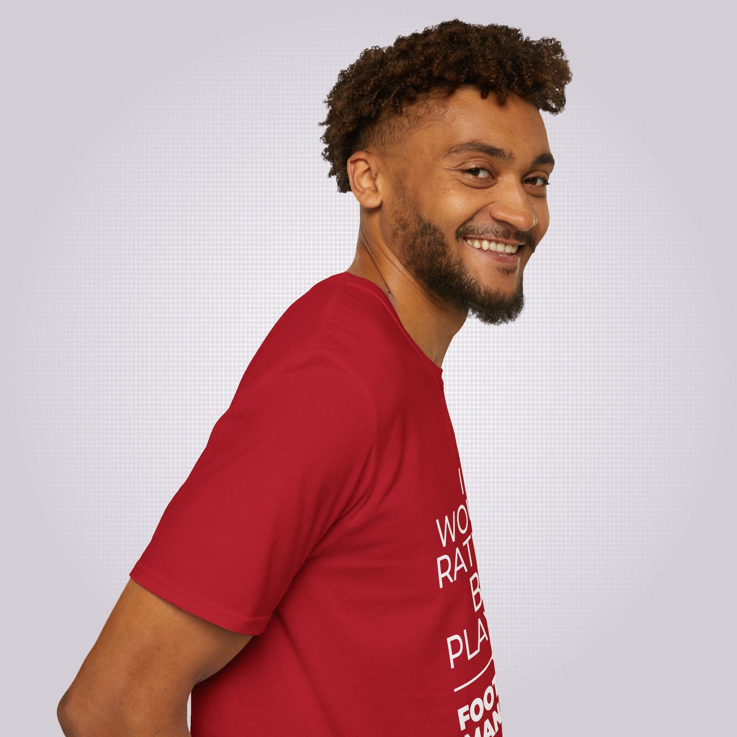 Side profile shot of a young mixed race man wearing the red t shirt his body is facing to the right as you look and he is looking at the camera 