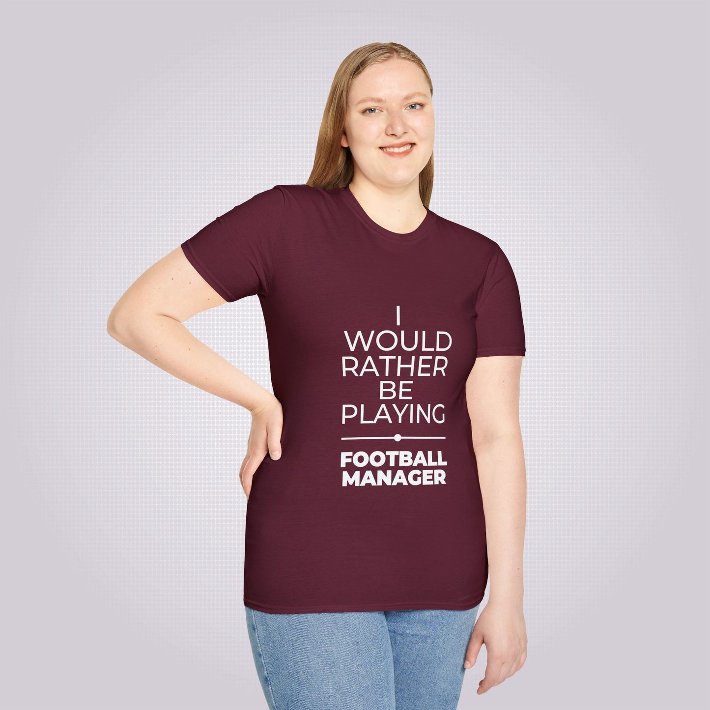 Young female model with fair hair smiles at camera with her arm on her hip wearing the maroon t shirt and jeans