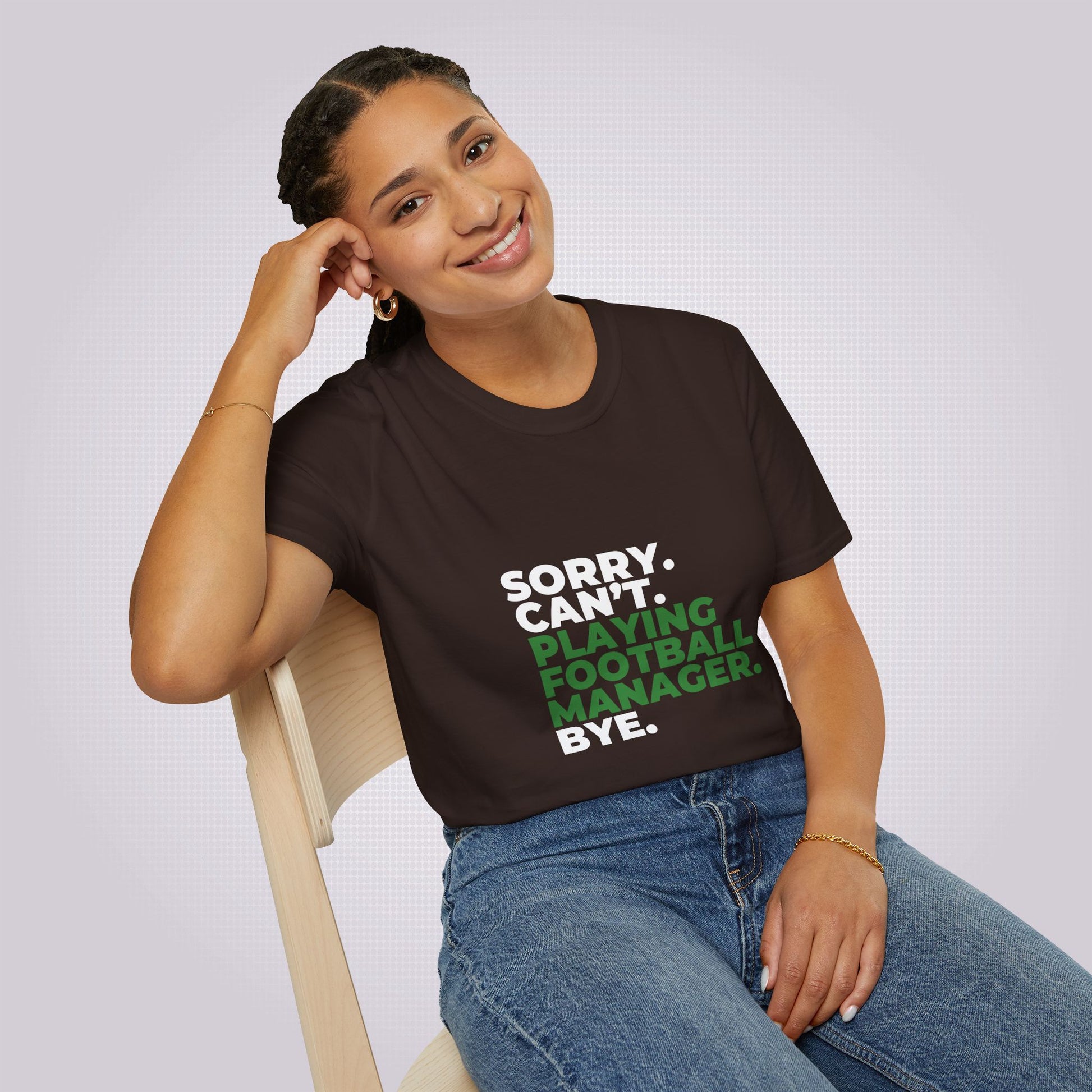 Young mixed race woman sits on a chair leaning on her elbow she is wearing the brown t shirt and jeans